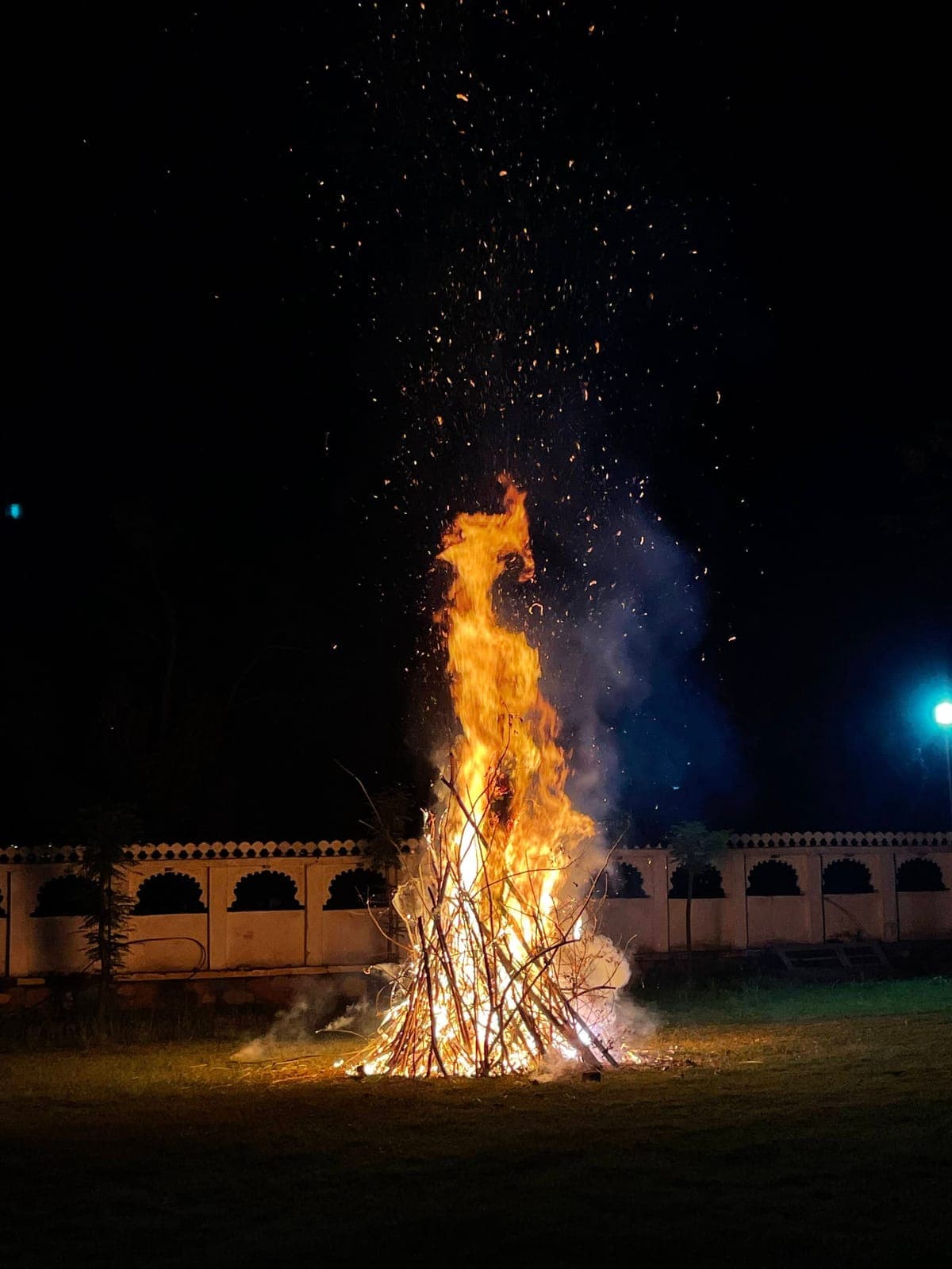 A bonfire burning on the lawn at Devendra Garh on a winter night, sparks rising against the dark